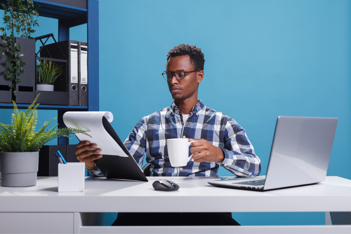 company-office-worker-having-documentation-clipboard-coffee-cup-looking-project-management-charts-young-african-american-employee-sitting-modern-workspace-while-reviewing-paperwork