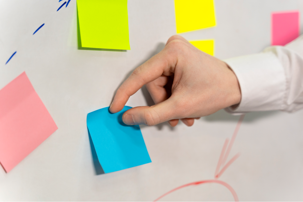 hand-sticking-blue-post-it-board